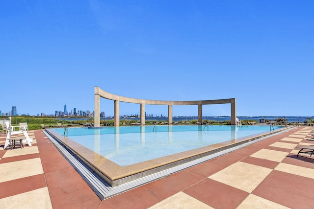 view of swimming pool featuring a water view and a city view