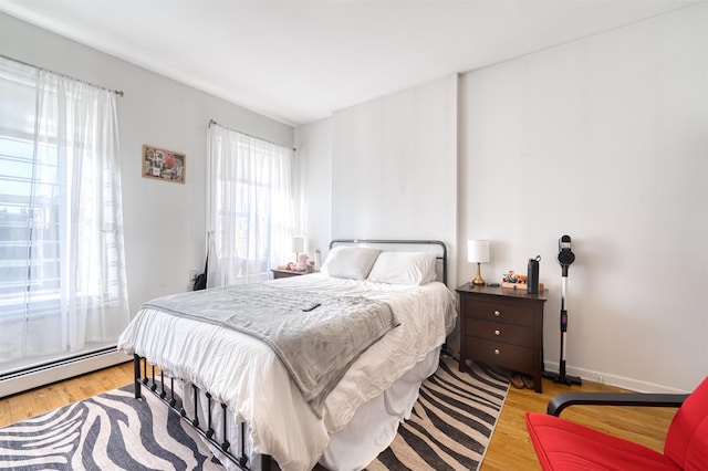 bedroom with light hardwood / wood-style flooring and a baseboard heating unit