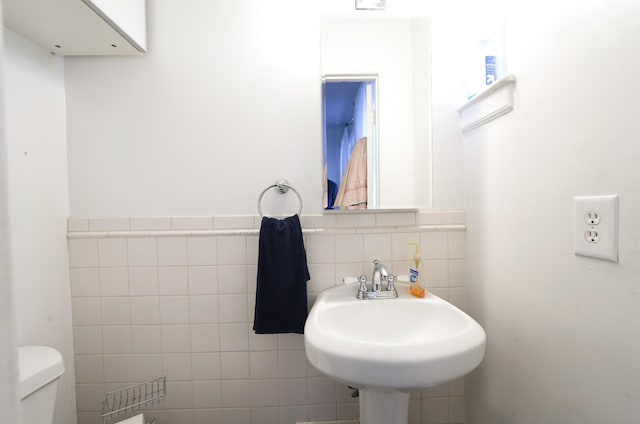 bathroom with sink, tile walls, and toilet