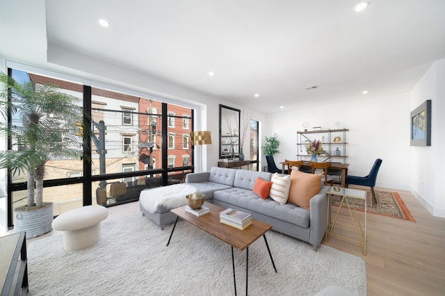 living area with light wood-style flooring, visible vents, and recessed lighting