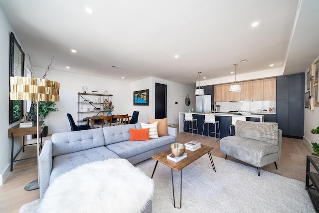 living room featuring light wood-type flooring, baseboards, and recessed lighting