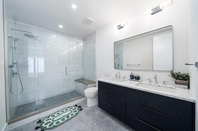 bathroom featuring toilet, a stall shower, double vanity, and a sink