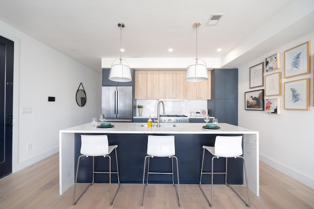 kitchen with a breakfast bar, light countertops, stainless steel built in fridge, a sink, and modern cabinets