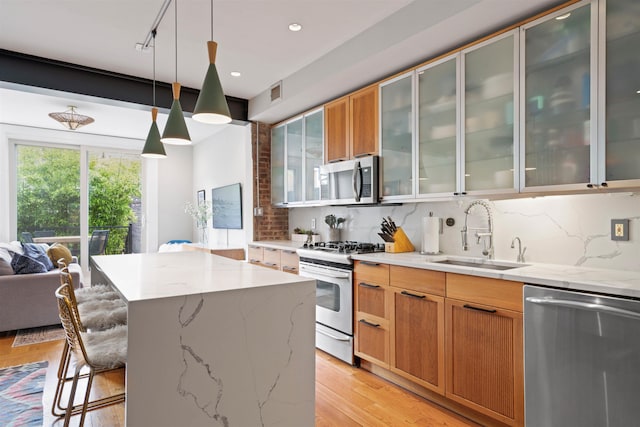 275 5th St Unit 1, Jersey City, NJ 07302 - kitchen with appliances with stainless steel finishes, tasteful backsplash, light wood finished floors, a kitchen breakfast bar, and light stone countertops