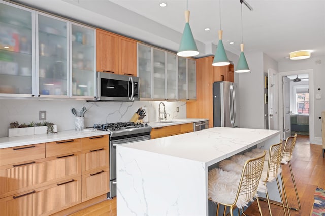 275 5th St Unit 1, Jersey City, NJ 07302 - kitchen with appliances with stainless steel finishes, light wood-style flooring, a kitchen island, a kitchen breakfast bar, and recessed lighting