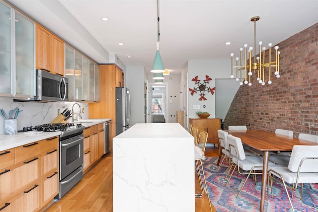 275 5th St Unit 1, Jersey City, NJ 07302 - kitchen with appliances with stainless steel finishes, a center island, light wood-type flooring, brick wall, and decorative light fixtures