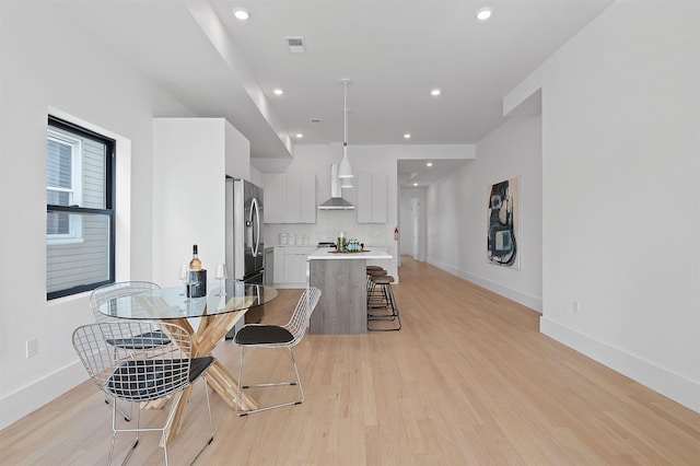 206 Fulton Ave # 2, Jersey City, NJ 07305 - kitchen featuring stainless steel fridge, wall chimney exhaust hood, light countertops, a kitchen island, and light wood finished floors