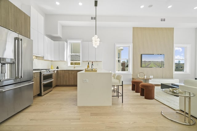 44 Bleecker St Unit 2, Jersey City, NJ 07307 - kitchen with appliances with stainless steel finishes, modern cabinets, a breakfast bar area, brown cabinets, and recessed lighting