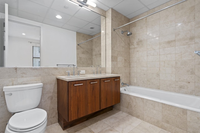 full bathroom with toilet, tiled shower / bath, tile walls, vanity, and tile patterned flooring