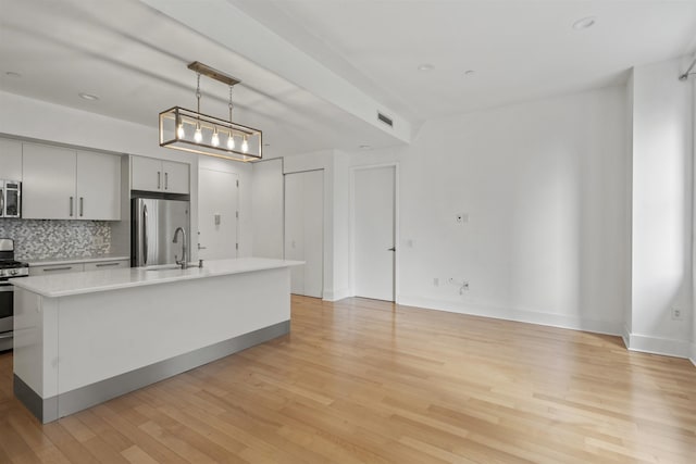 kitchen featuring hanging light fixtures, light wood-type flooring, gray cabinets, stainless steel appliances, and backsplash