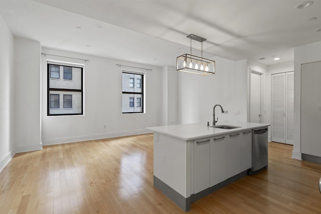 kitchen featuring sink, dishwasher, an island with sink, pendant lighting, and light hardwood / wood-style floors