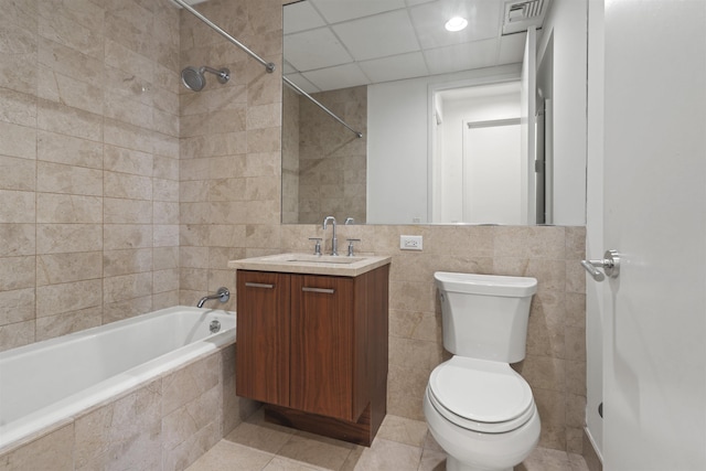 full bathroom featuring tile walls, tile patterned flooring, tiled shower / bath combo, vanity, and toilet