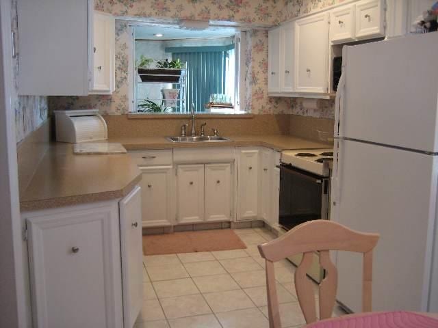 kitchen with sink, light tile patterned floors, white cabinets, and white fridge