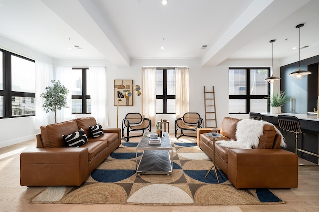 living room with beam ceiling, light wood-type flooring, and plenty of natural light