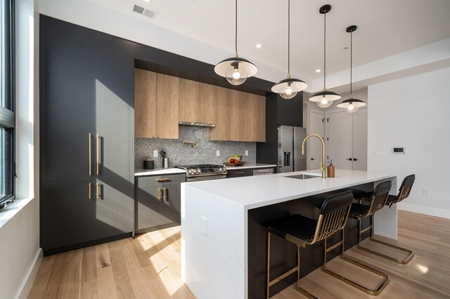 kitchen featuring pendant lighting, light hardwood / wood-style floors, an island with sink, and a breakfast bar area