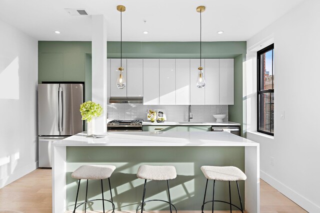 kitchen with a center island, decorative backsplash, appliances with stainless steel finishes, a kitchen breakfast bar, and sink