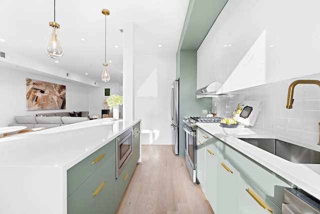 kitchen featuring stainless steel appliances, sink, decorative light fixtures, white cabinetry, and backsplash