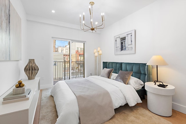 bedroom with light hardwood / wood-style floors, an inviting chandelier, and access to exterior