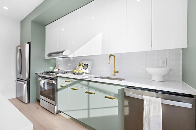 kitchen with light hardwood / wood-style flooring, stainless steel appliances, decorative backsplash, white cabinetry, and sink