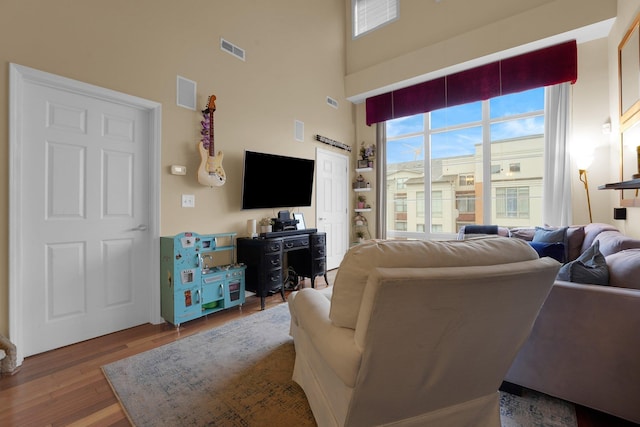 living room with wood-type flooring and a towering ceiling