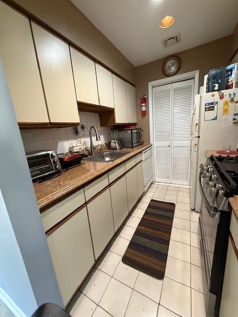 603 55th St Unit 204, West New York, NJ 07093 - kitchen with black range with gas stovetop, a sink, white dishwasher, tasteful backsplash, and white cabinets
