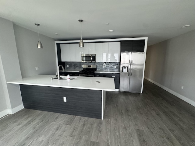 kitchen with stainless steel appliances, sink, white cabinets, tasteful backsplash, and hanging light fixtures