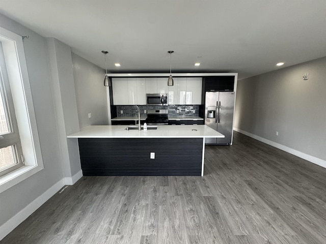 kitchen with hanging light fixtures, stainless steel appliances, tasteful backsplash, white cabinets, and sink