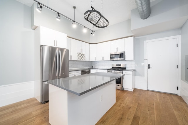 kitchen with light wood-style flooring, backsplash, appliances with stainless steel finishes, and a kitchen island