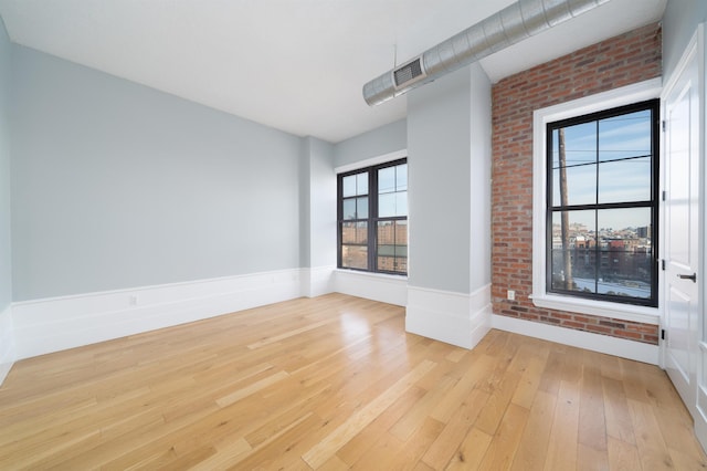 100 Paterson Plank Rd Unit 229, Jersey City, NJ 07030 - empty room featuring a wainscoted wall, visible vents, brick wall, and light wood-style floors