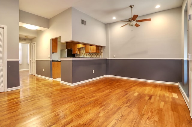 187 Wayne St Unit 208C, Jersey City, NJ 07302 - kitchen featuring brown cabinetry, freestanding refrigerator, ceiling fan, light wood finished floors, and a peninsula