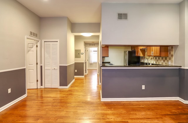 187 Wayne St Unit 208C, Jersey City, NJ 07302 - kitchen featuring freestanding refrigerator, brown cabinetry, dark countertops, light wood finished floors, and backsplash