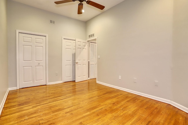 187 Wayne St Unit 208C, Jersey City, NJ 07302 - unfurnished bedroom with multiple closets, light wood-style flooring, a towering ceiling, and a ceiling fan