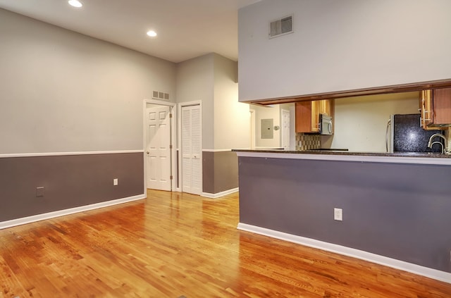 187 Wayne St Unit 208C, Jersey City, NJ 07302 - kitchen with freestanding refrigerator, stainless steel microwave, light wood-type flooring, recessed lighting, and electric panel