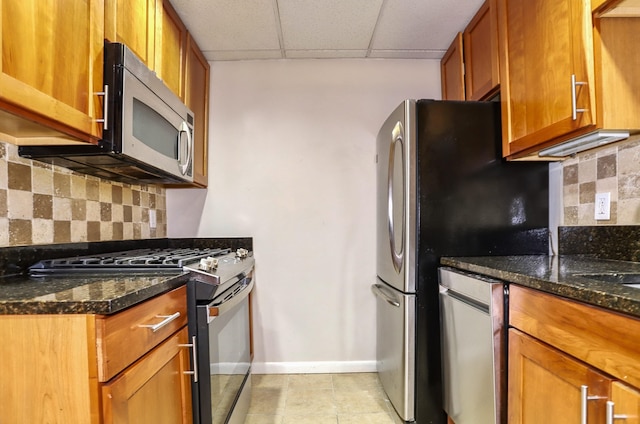 187 Wayne St Unit 208C, Jersey City, NJ 07302 - kitchen featuring stainless steel appliances, brown cabinets, a drop ceiling, dark stone counters, and backsplash