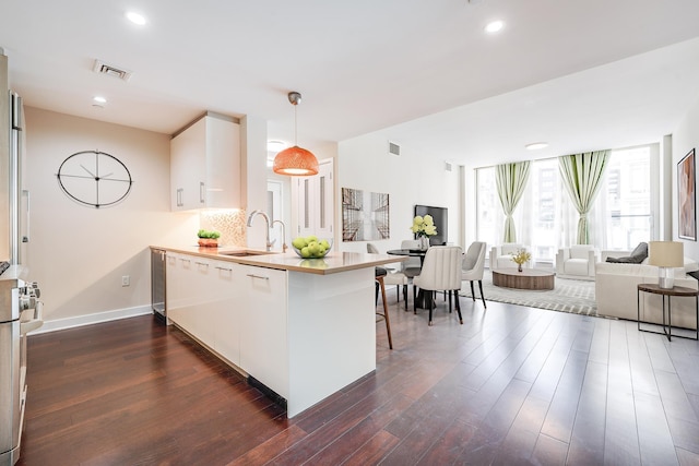 kitchen featuring sink, kitchen peninsula, decorative light fixtures, a kitchen bar, and decorative backsplash