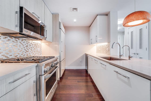 kitchen featuring white cabinets, sink, hanging light fixtures, dark hardwood / wood-style flooring, and stainless steel appliances