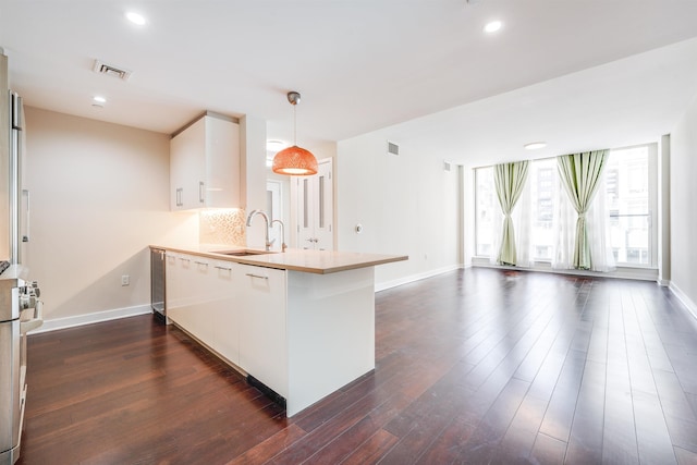 kitchen with sink, hanging light fixtures, dark hardwood / wood-style floors, kitchen peninsula, and decorative backsplash