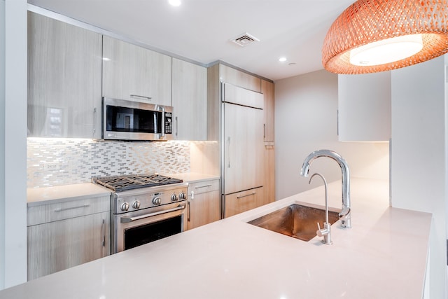 kitchen featuring light brown cabinets, premium appliances, backsplash, and sink