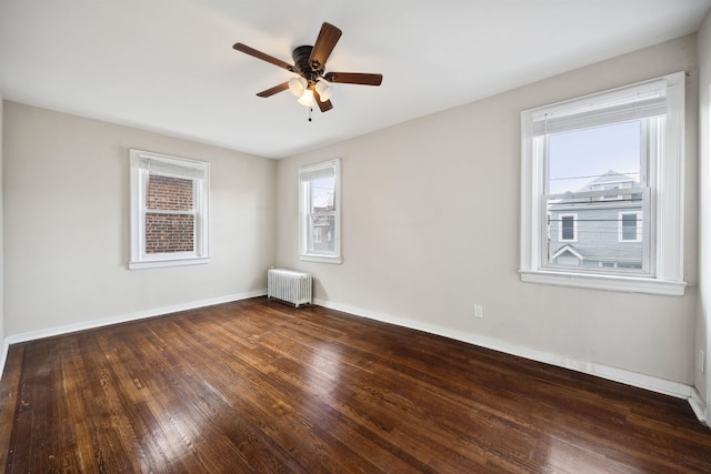 spare room featuring dark hardwood / wood-style floors, ceiling fan, and radiator heating unit