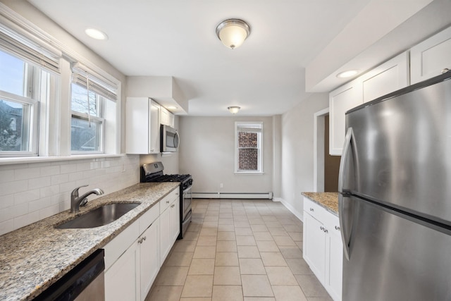 kitchen featuring sink, baseboard heating, light stone counters, white cabinets, and appliances with stainless steel finishes