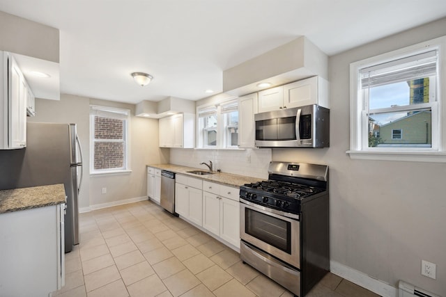 kitchen with tasteful backsplash, stainless steel appliances, baseboard heating, sink, and white cabinetry