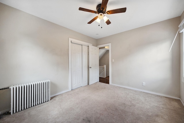 unfurnished bedroom with a closet, ceiling fan, radiator heating unit, and carpet