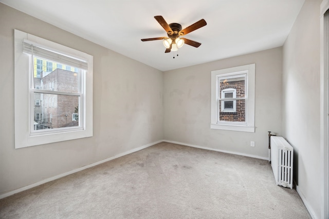 carpeted empty room featuring radiator heating unit and ceiling fan