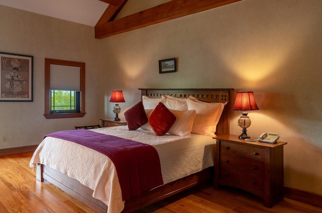 bedroom featuring lofted ceiling with beams and light hardwood / wood-style flooring