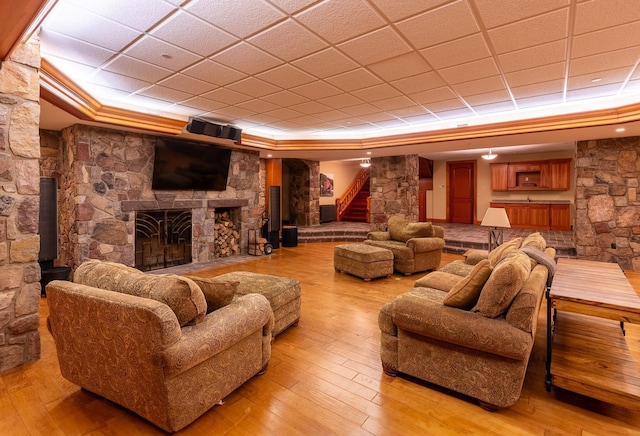 home theater with a raised ceiling, a stone fireplace, and light hardwood / wood-style floors