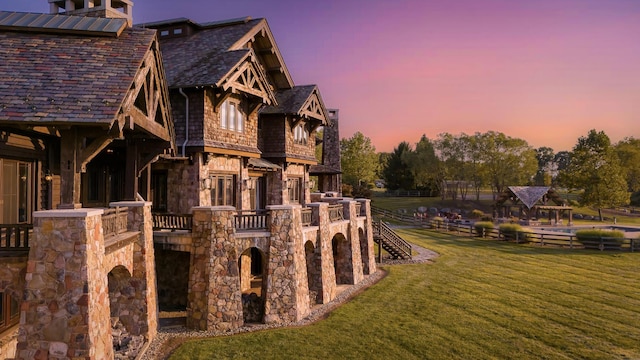 property exterior at dusk featuring a lawn