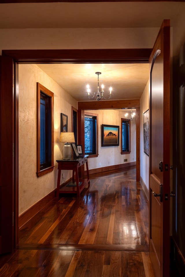 corridor featuring dark wood-type flooring and a chandelier