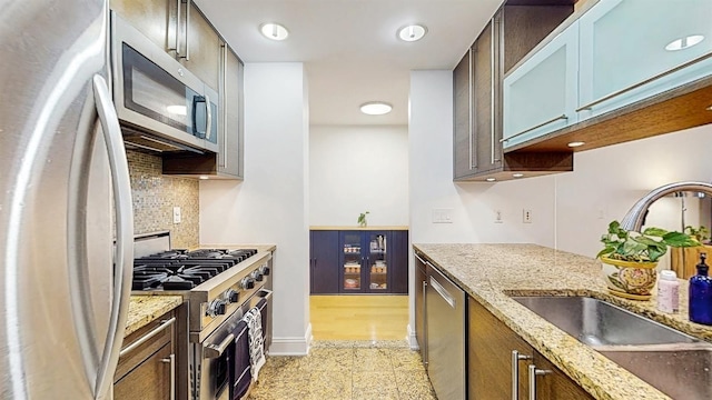 10 Regent St Unit 201, Jersey City, NJ 07302 - kitchen featuring appliances with stainless steel finishes, a sink, tasteful backsplash, baseboards, and light stone counters