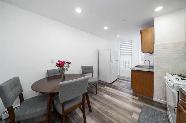 dining space featuring light wood-type flooring, a baseboard heating unit, and sink