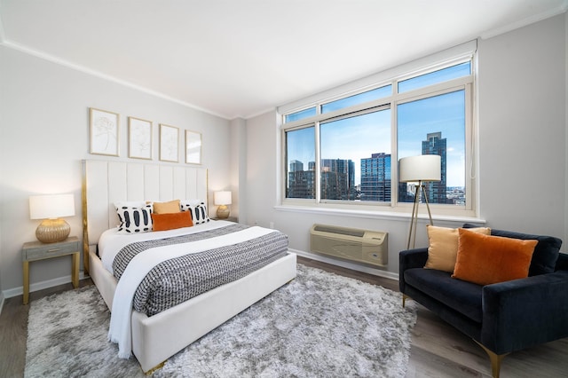 20 2nd St Unit 2503, Jersey City, NJ 07302 - bedroom featuring an AC wall unit, wood finished floors, ornamental molding, a view of skyline, and baseboards